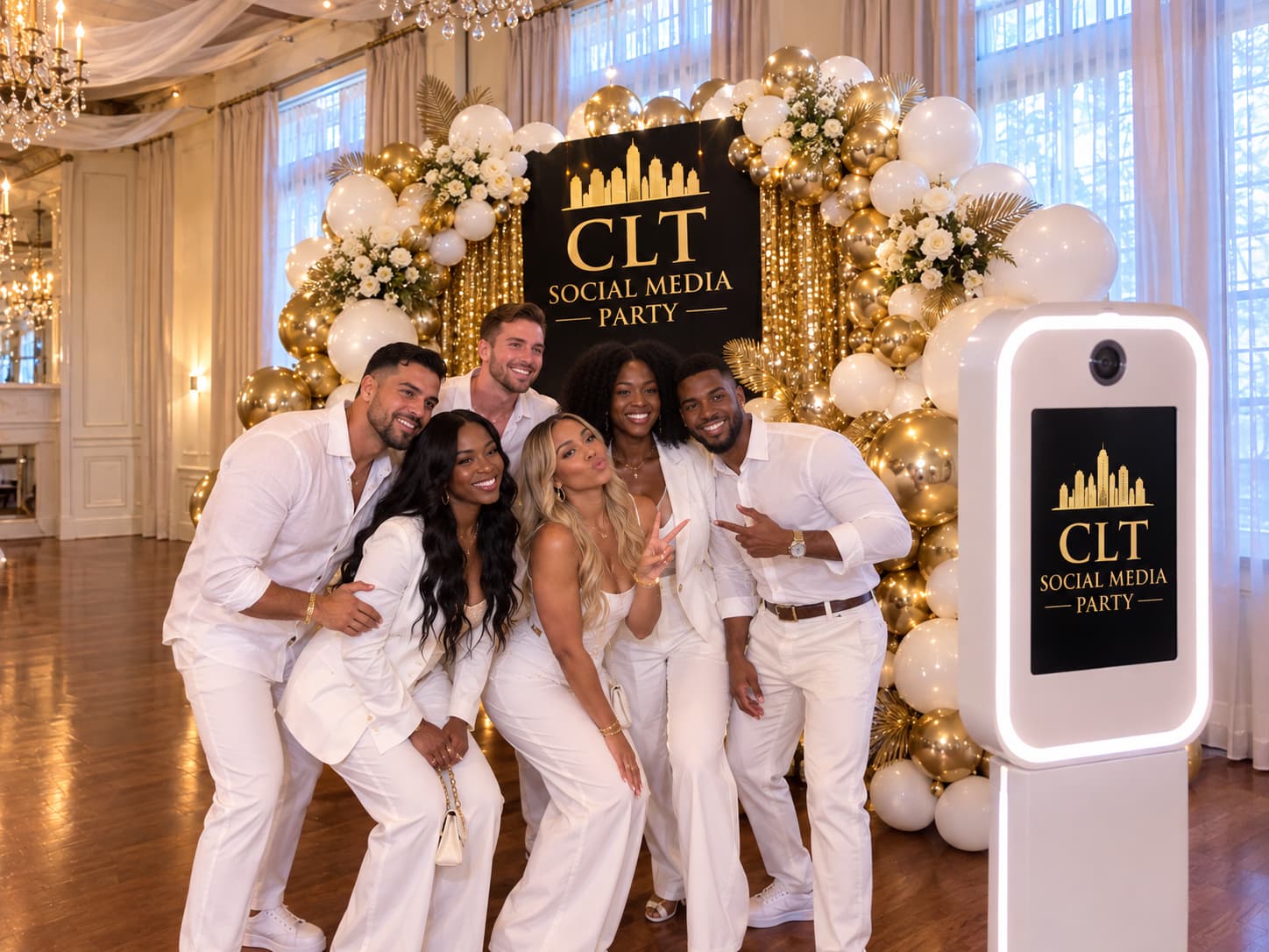 Six people in white pose before a balloon arch at the CLT Social Media Party.